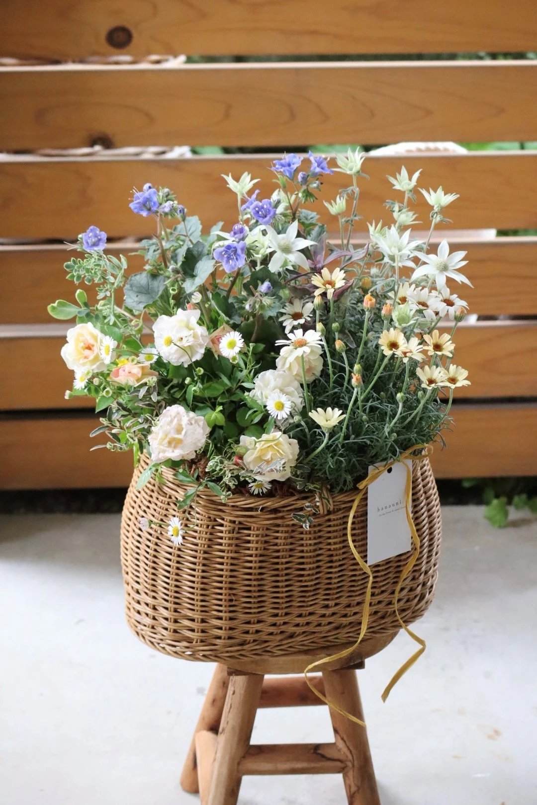籠に青や白の花と葉を寄せ植えしたブリコラージュフラワー