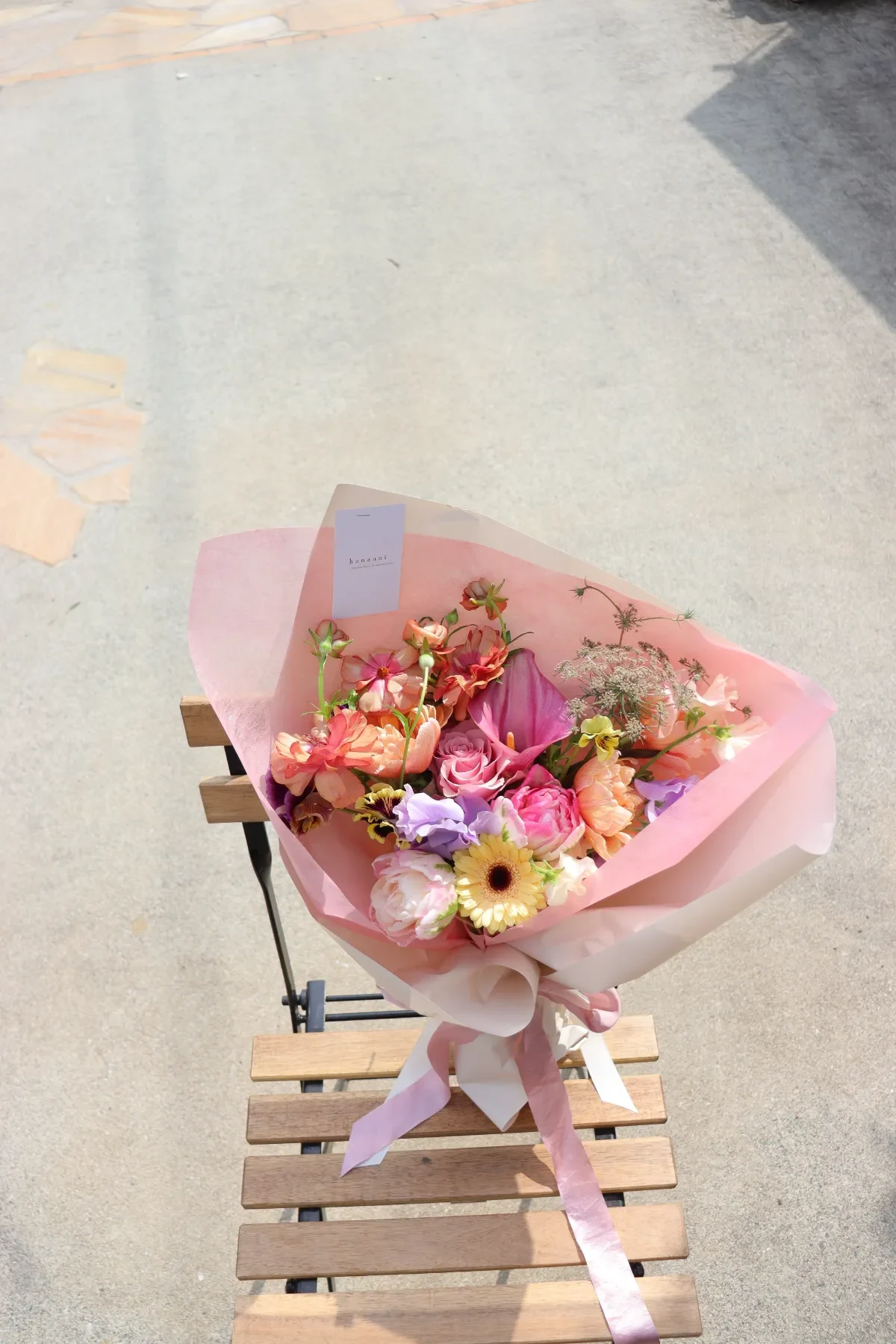 ピンクの包装紙で包んだ、色とりどりの季節の花束