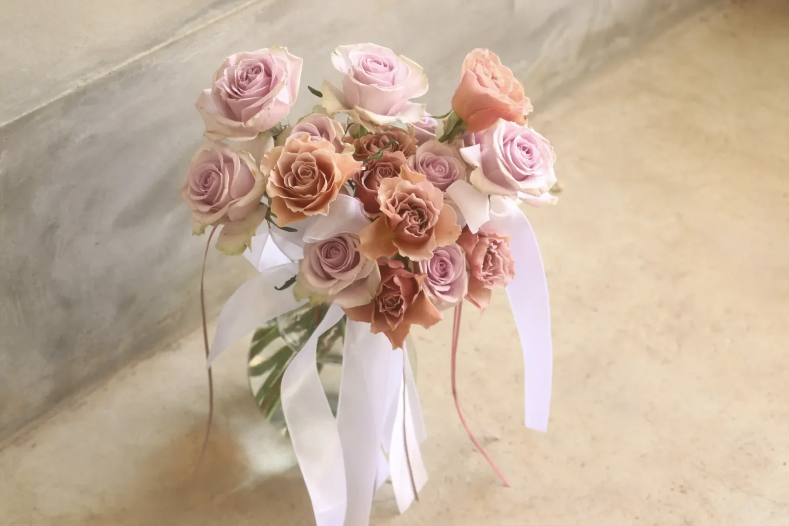 淡いピンクと茶色のバラに白いリボンを合わせたhanauni.の花束